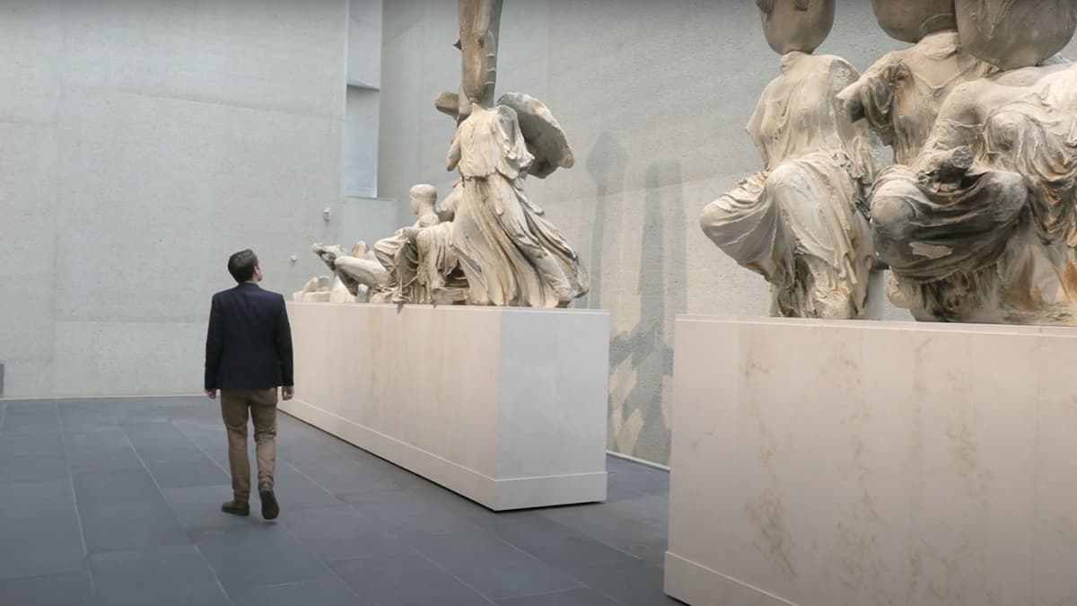 A video still of a man walking through a gallery space