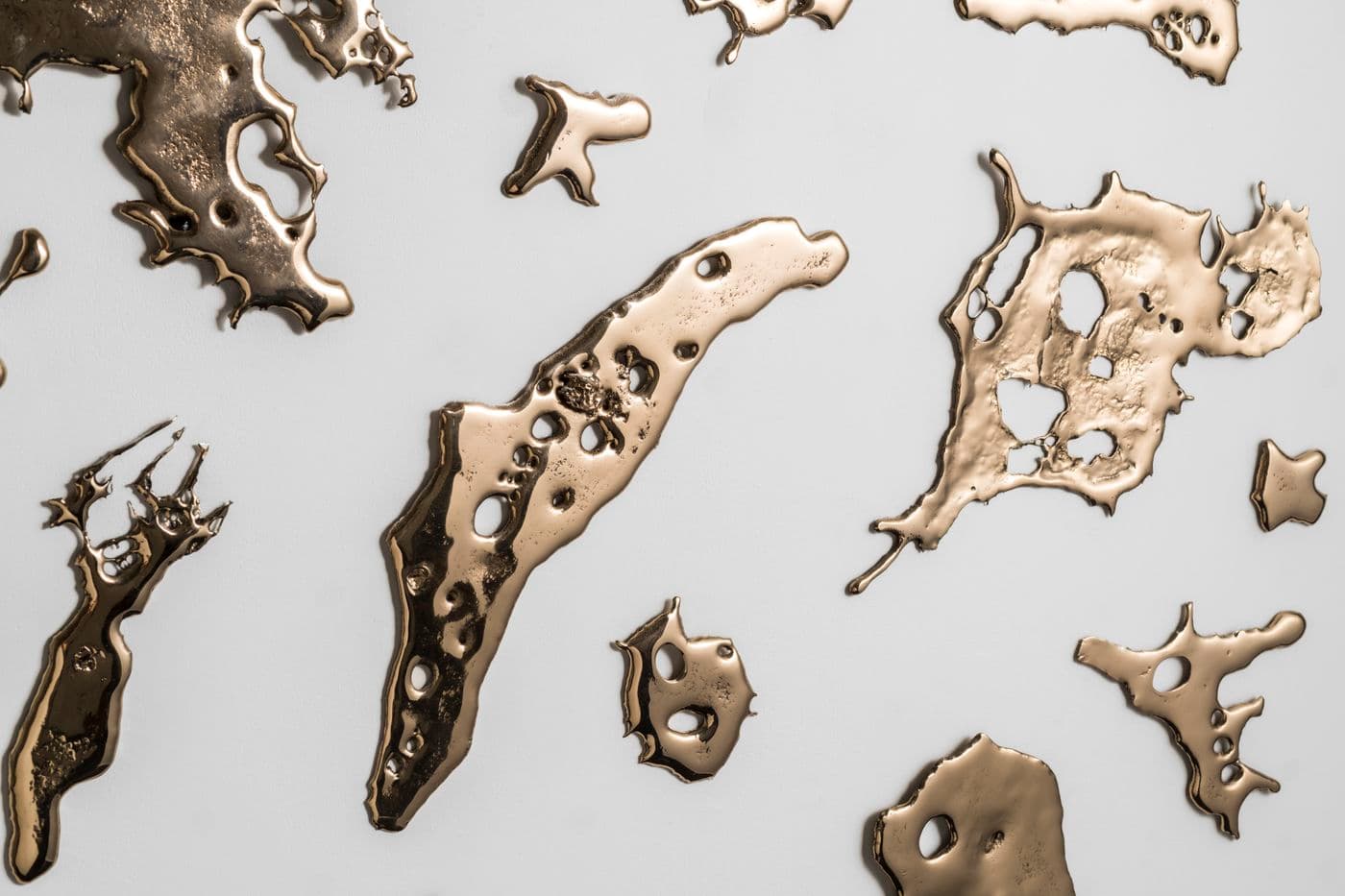 close up detail of pieces of flung bronze mounted on a wall