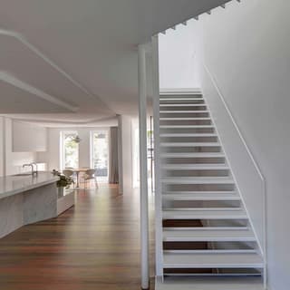 Photograph of domestic interior with white staircase and wooden floor boards