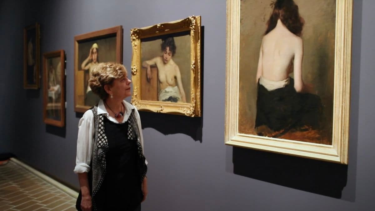 Video still of lady looking at paintings