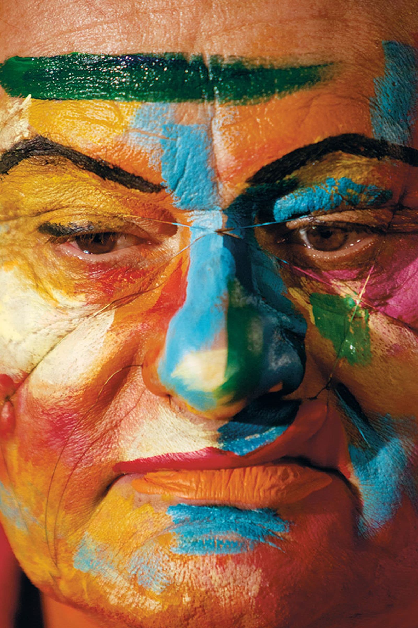 Close-up photography of a man with sections of his face painted in bright colours