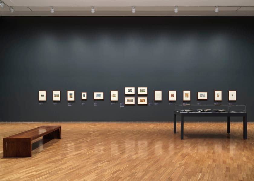 A dark grey wall with small works of art on it