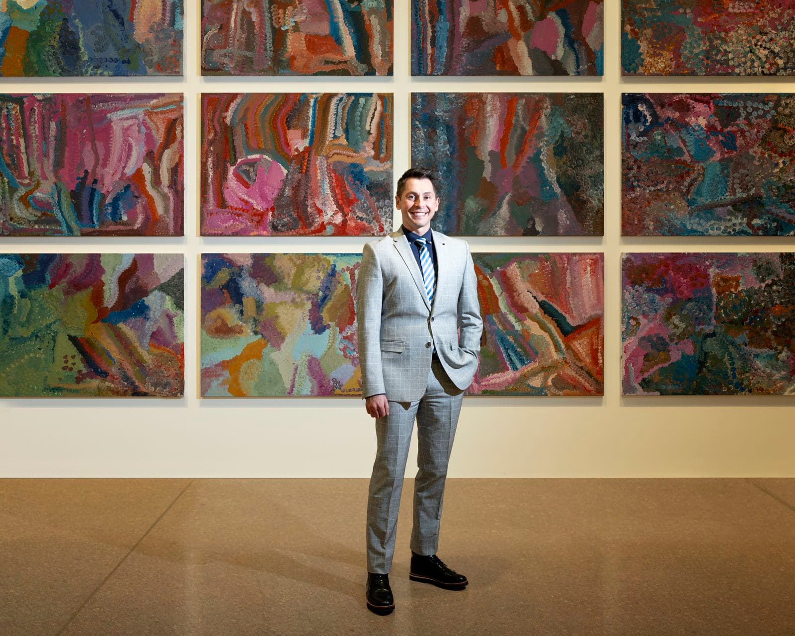 A man standing in front of a colourful work of art series