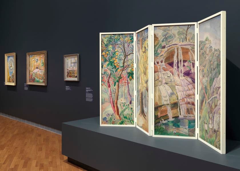 A work of art that is standing like an accordion on a plinth, and three smaller works in the distance on the wall