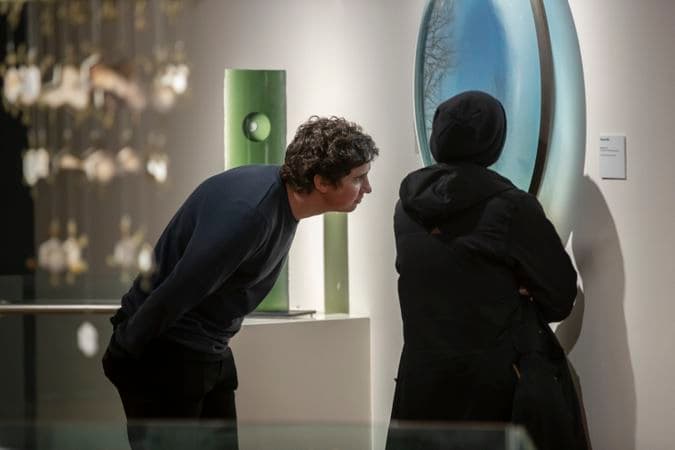 Two people are standing in a gallery looking at a work or art on the wall