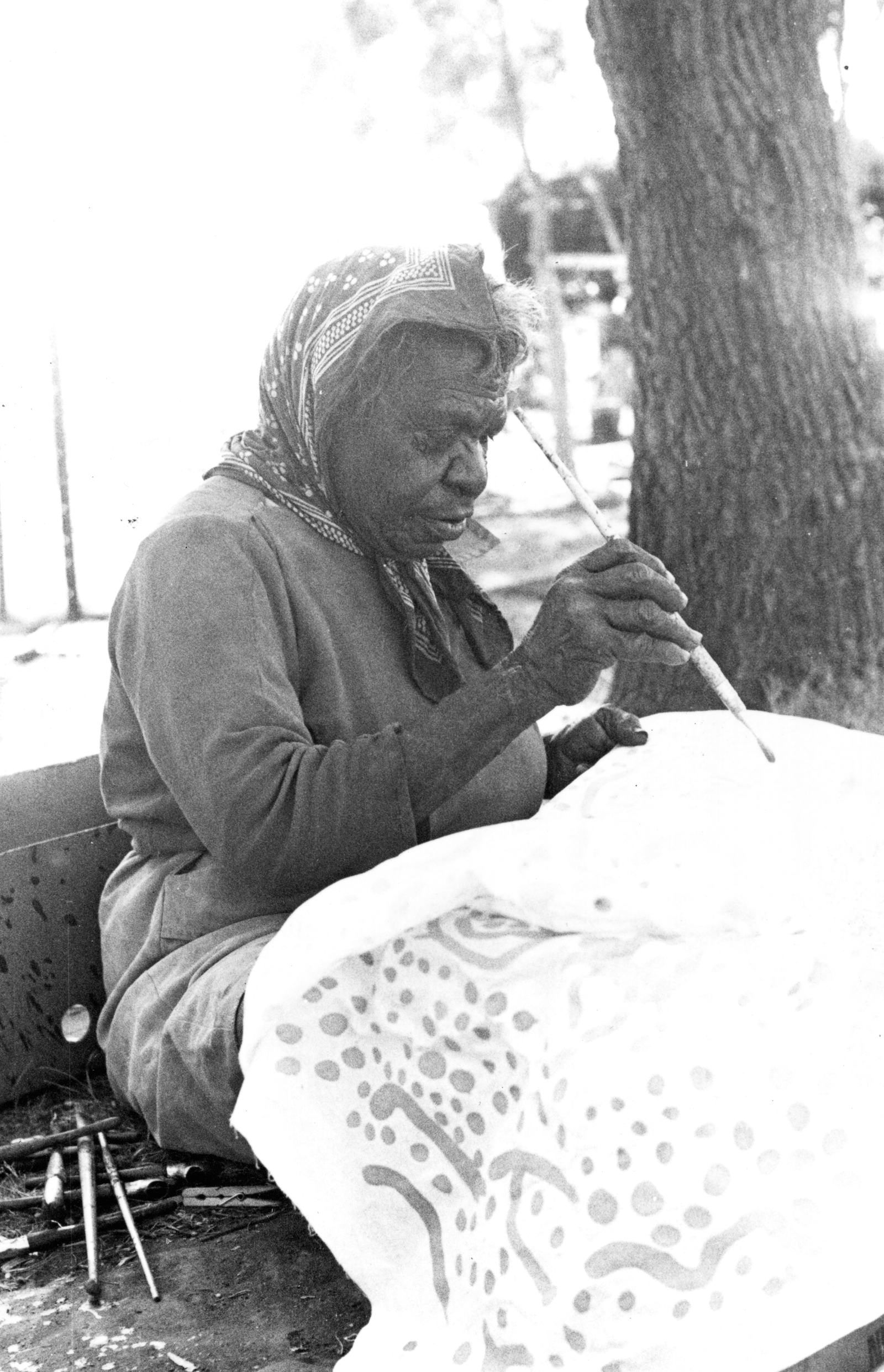 Black and white photograph of a woman painting on fabric