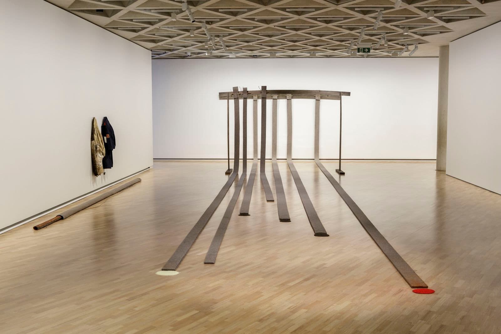 An installation by Joseph Beuys with seven large metal poles coming down a wall and across the floor.