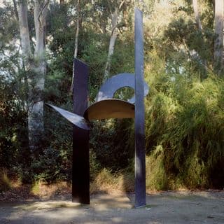 A steel and aluminium black sculpture of two large rectangular shapes flanking three circular shapes, one of which that has a circular opening within it