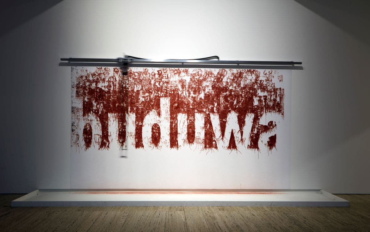 A white wall, with the text 'buduwa' written in earth pigment
