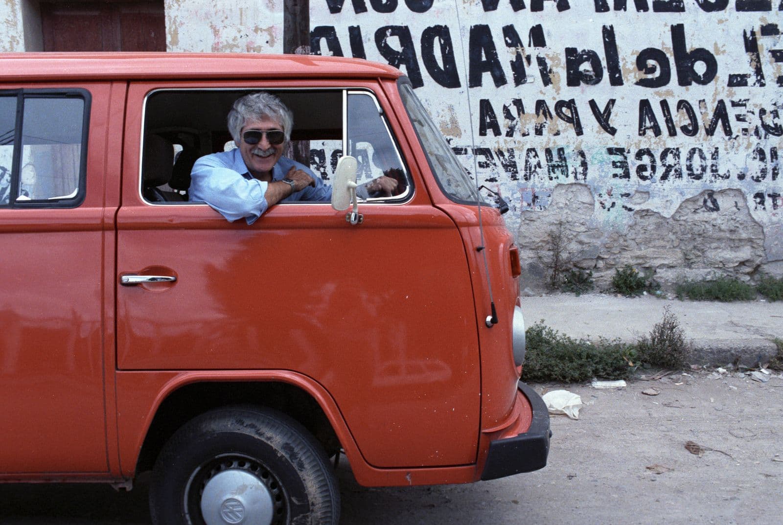 Man wearing sunglasses sitting in the driver's side of a red van