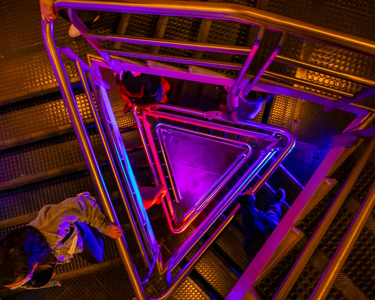 people walking down a triangular staircase