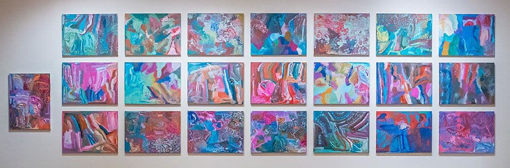 In this photo 22 brightly coloured rectangular canvases are hanging together on a large gallery wall