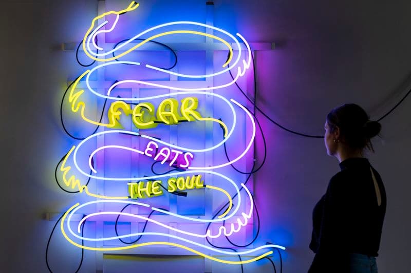 Photograph of woman looking at neon art in dark gallery