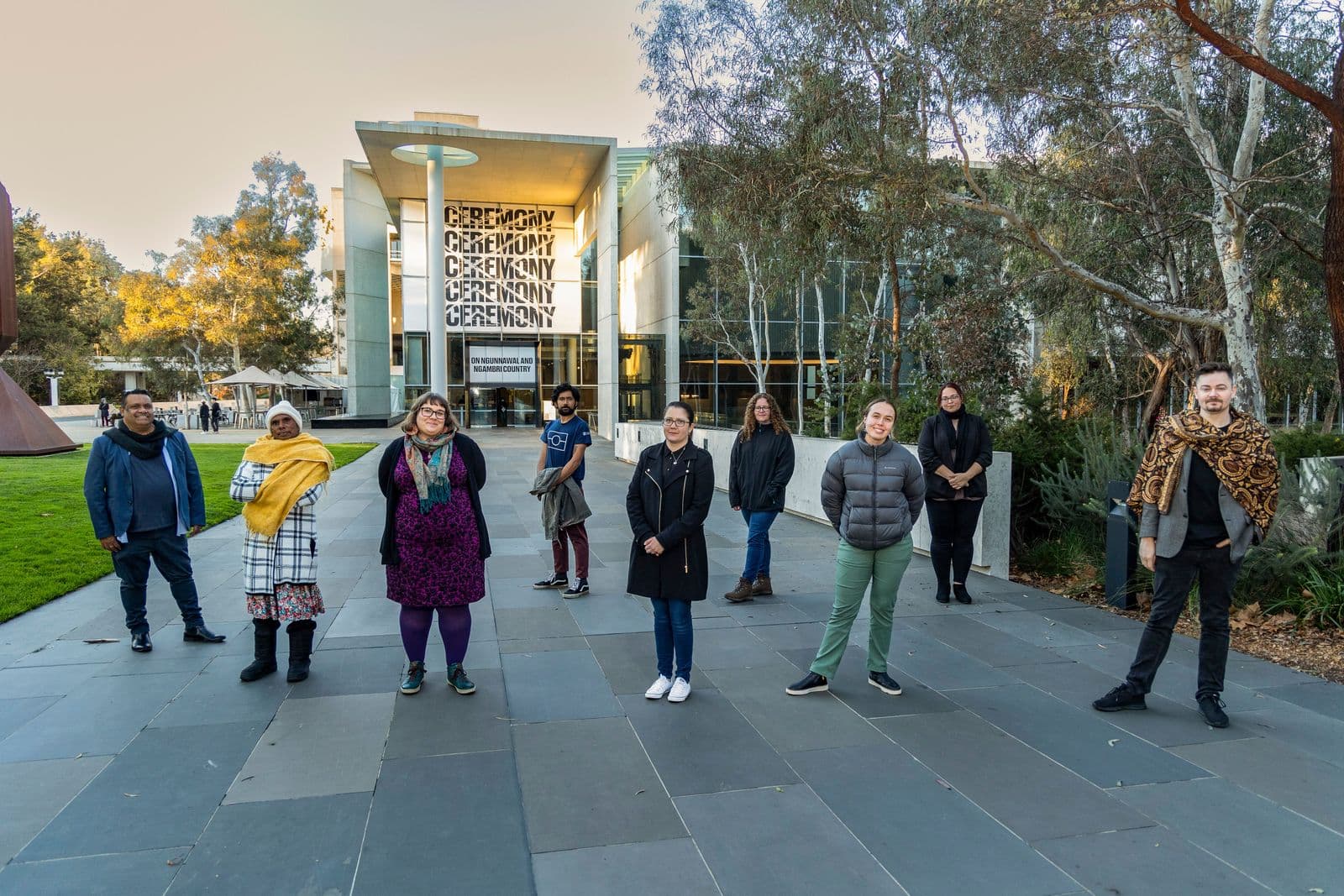 A group of people pose in front of the gallery facing the camera to have their photo taken