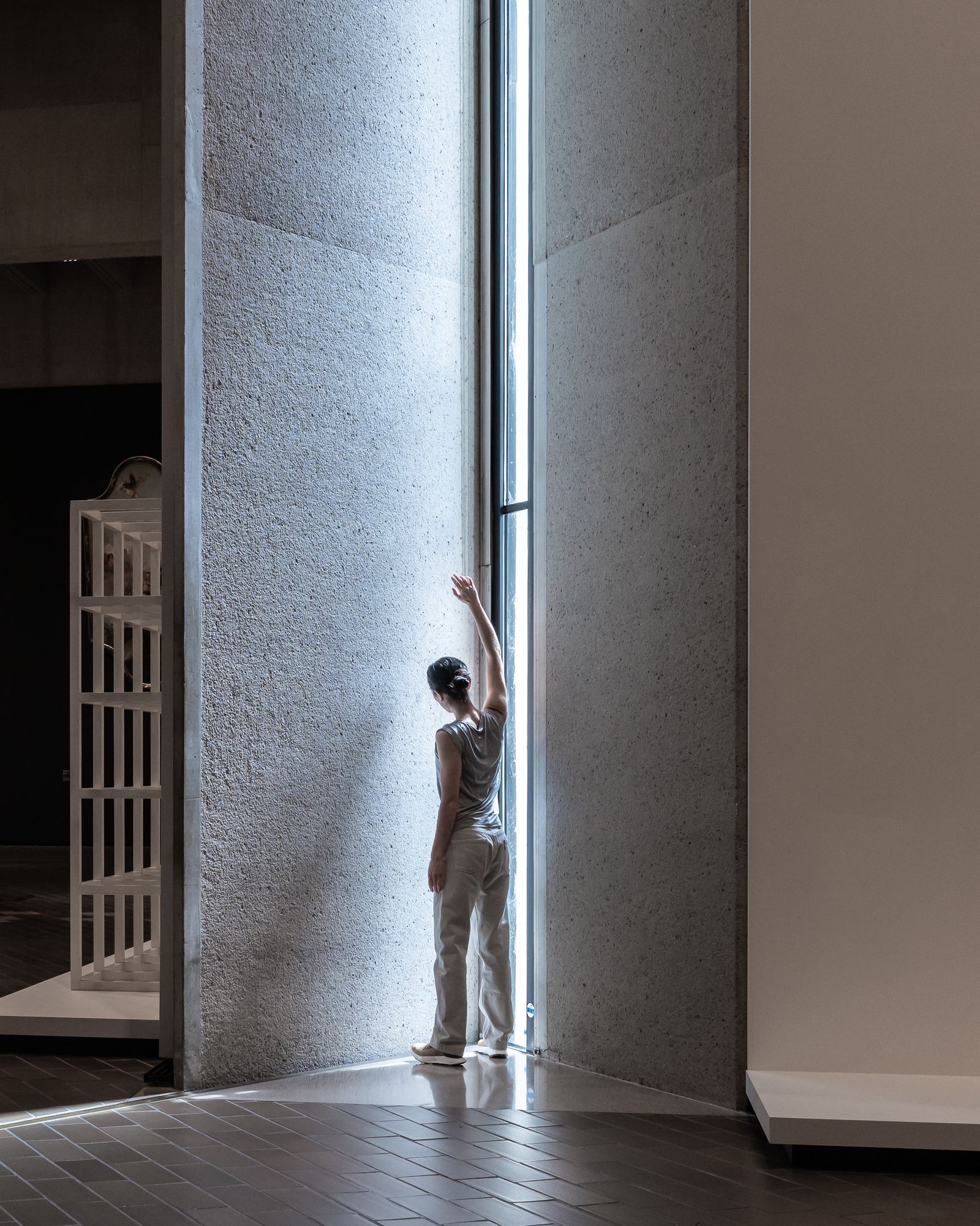 A dancers stands in the light from a window in the brutalist National Gallery architecture.