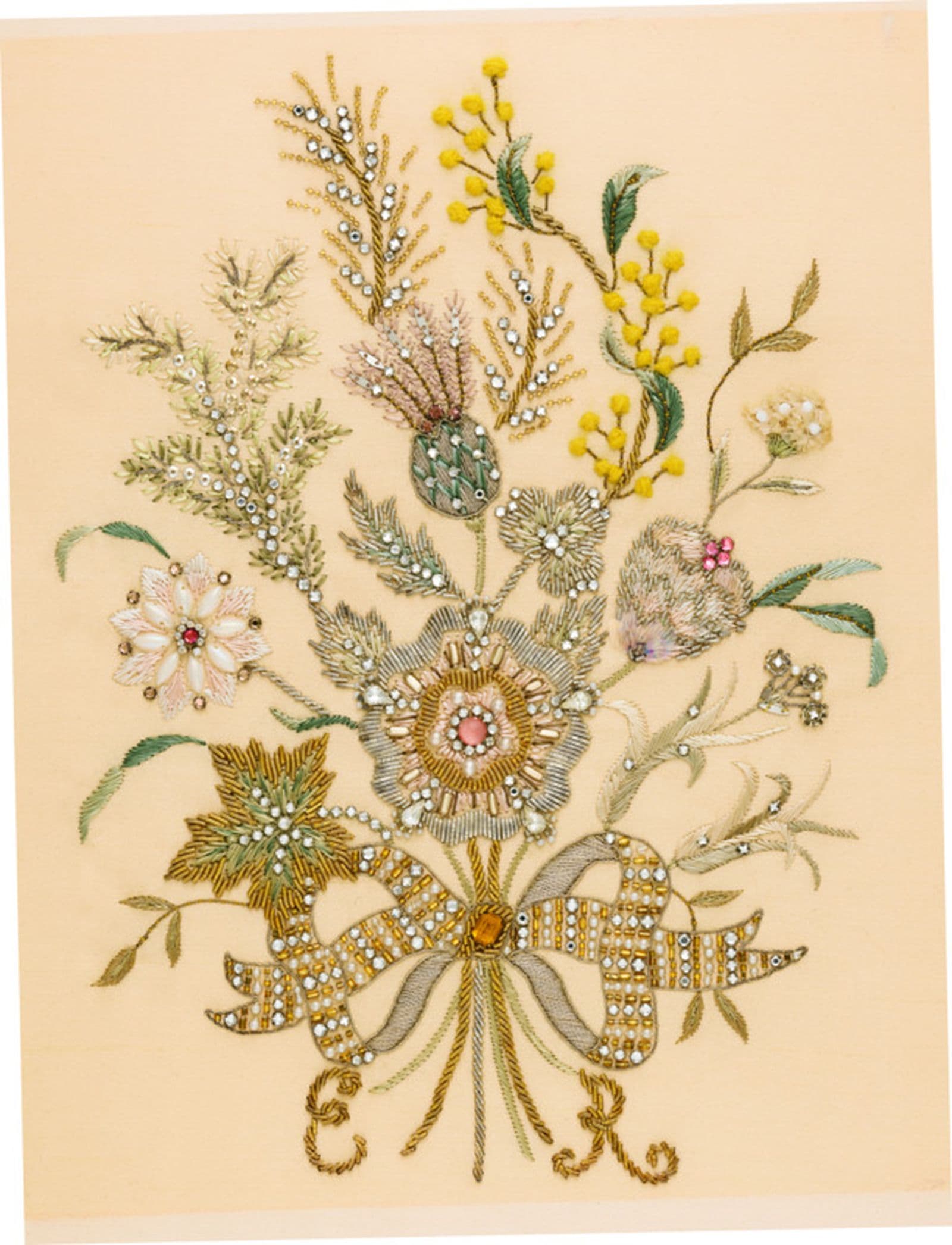 A patch of intricate beaded floral embroidery with a sprig of wattle