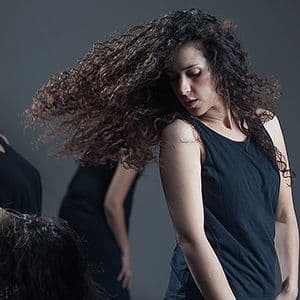A women with long brown hair is mid-motion swinging it over her shoulder