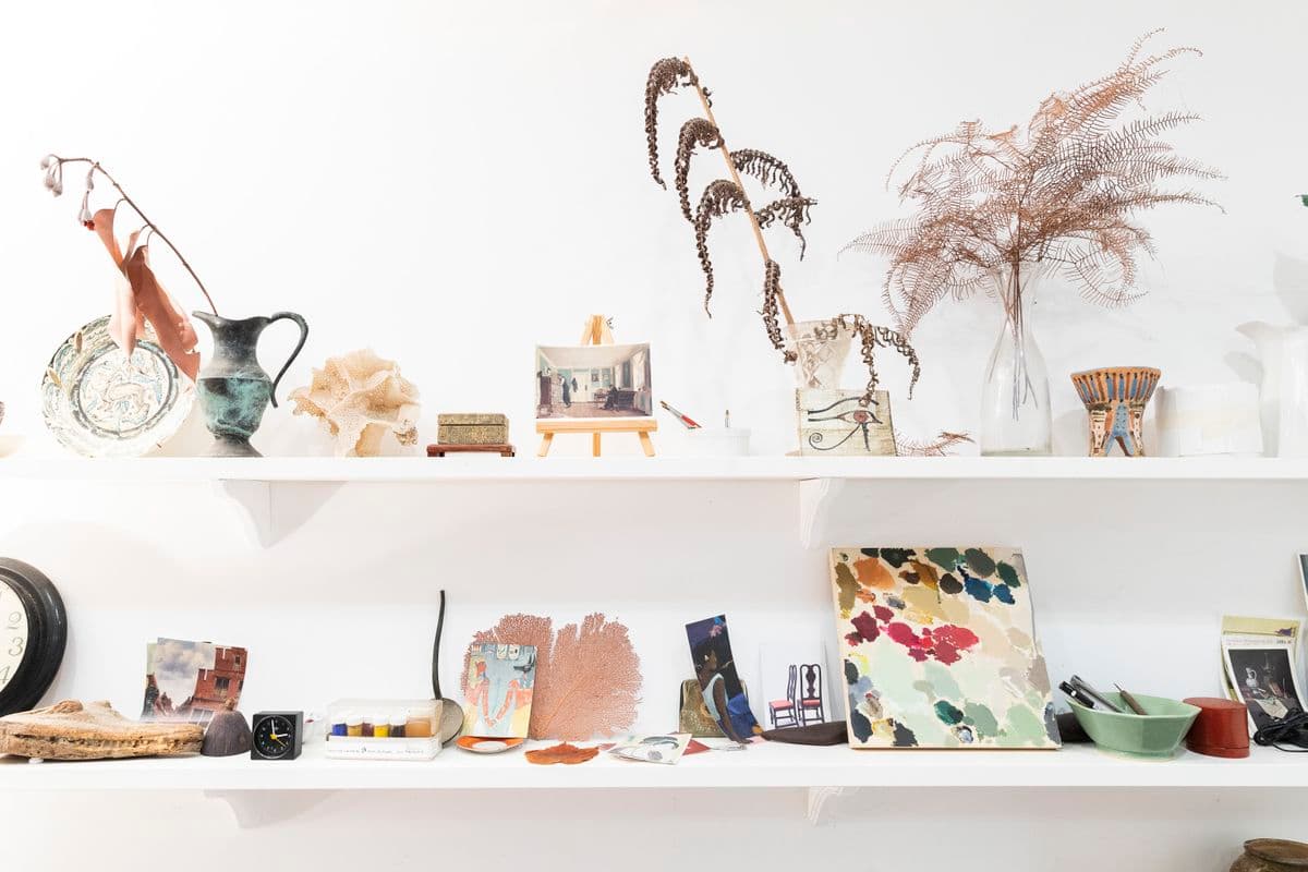 Two horizontal shelves with eclectic objects such a photographs, plant materials and ceramics