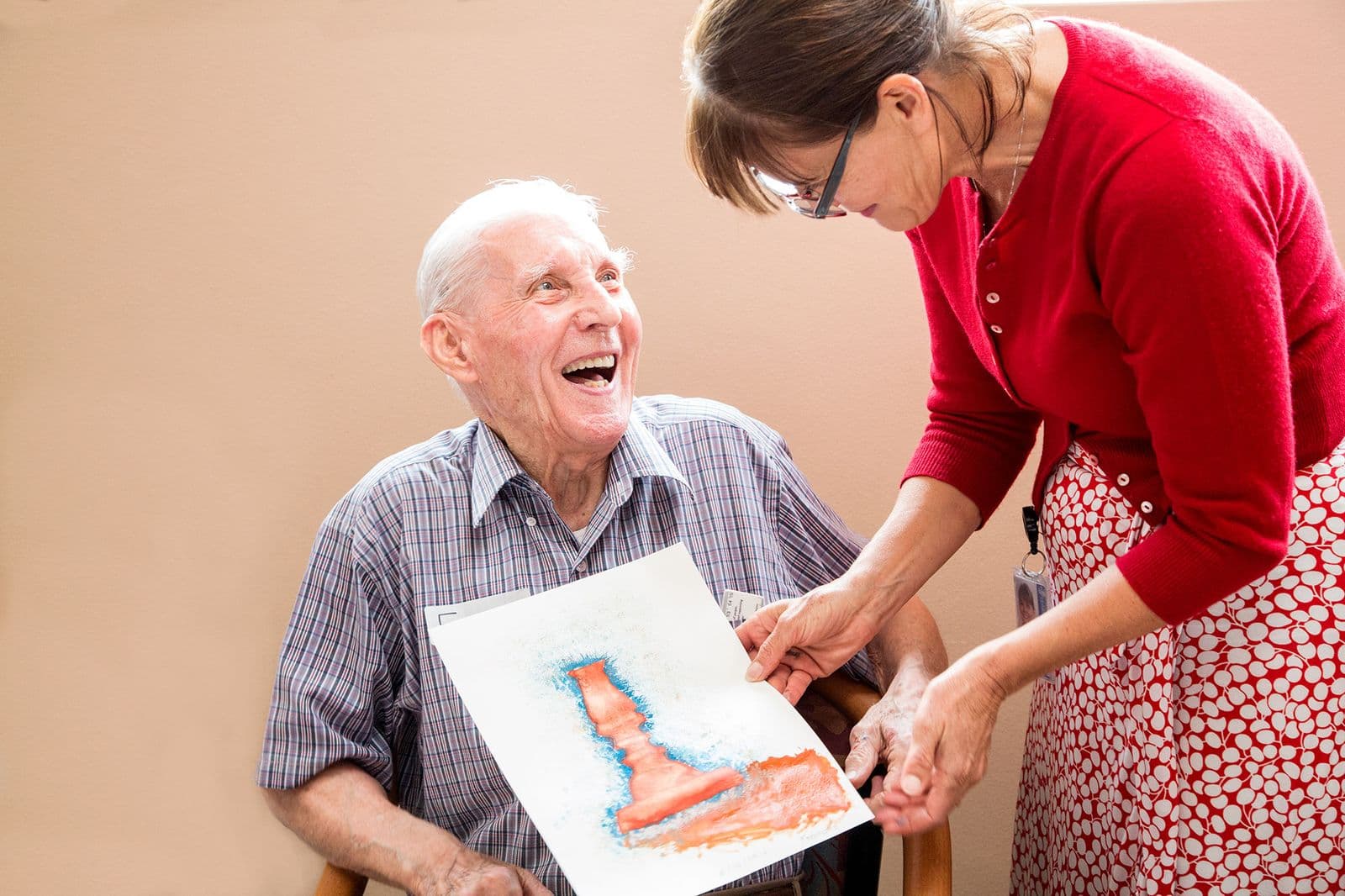 Photograph of man sitting and woman standing looking at artmaking