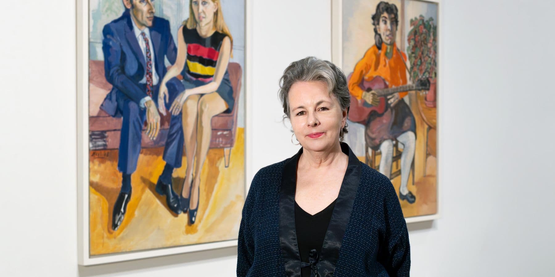 A picture of a woman in front of two works of art.