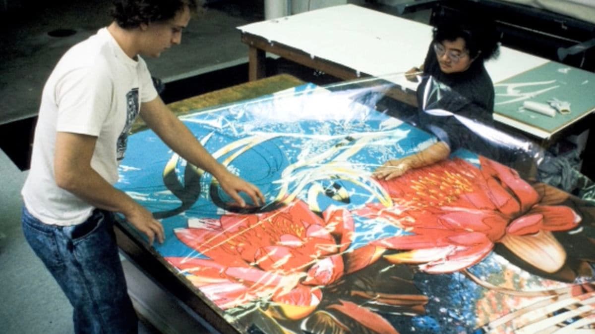 Video still of two people working on an artwork in studio.