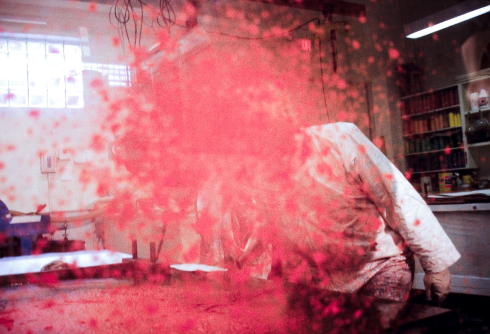 Male artist spraying coloured paper pulp onto paper