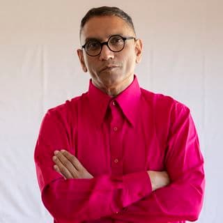 Photo of a man wearing a red shirt and crossing his arms