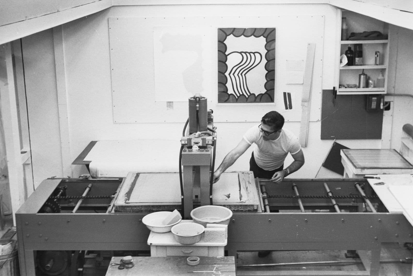 A photo taken from above of a man operating a hydraulic lithography press