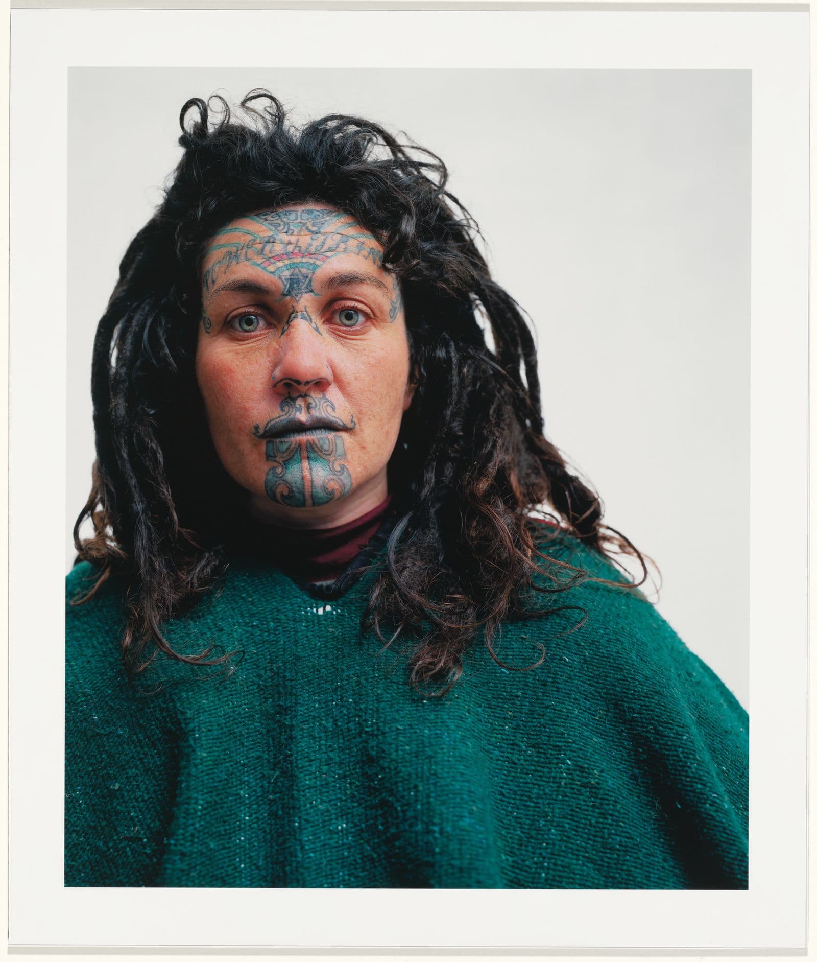 Photograph of Individual with long brown hair with traditional Maori face tattoos