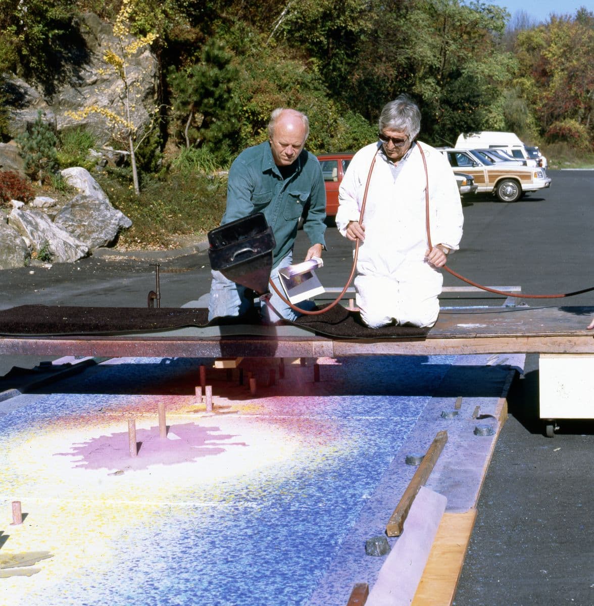 James Rosenquist and Kenneth Tyler operate a stucco spray gun to apply wet paper pulp to the ground for his print 'Time dust' from the 'Welcome to the water planet' series, Tyler Graphics, Mount Kisco, 1990