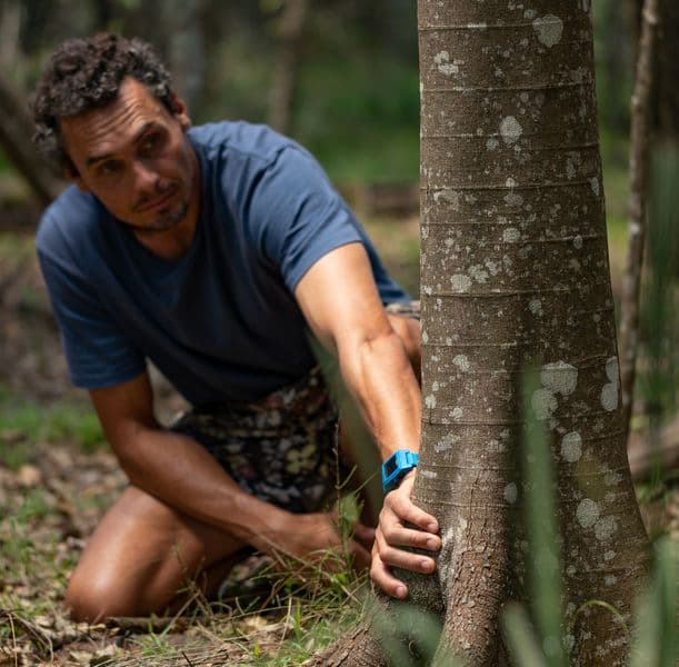 photograph of artist kneeling by tree in the bush
