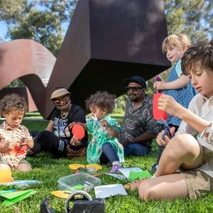 4 children and 2 adults sitting in a circle doing craft together.