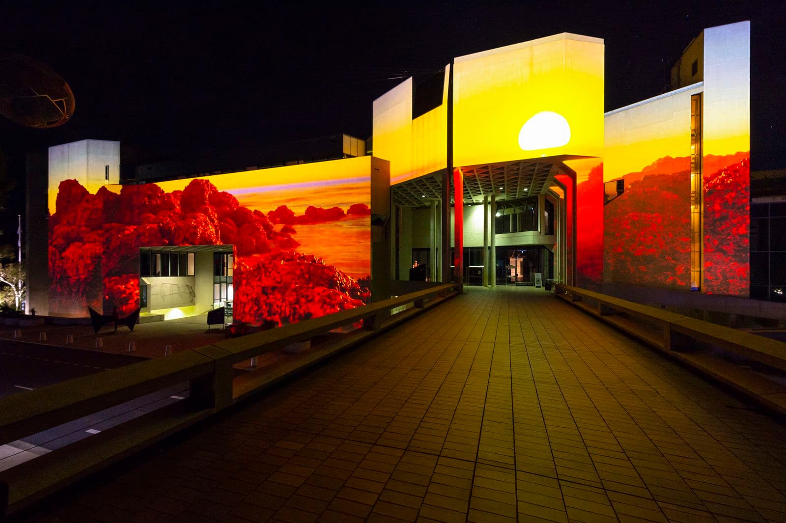 Projected image of the sun over a bush landscape on the side of the NGA building