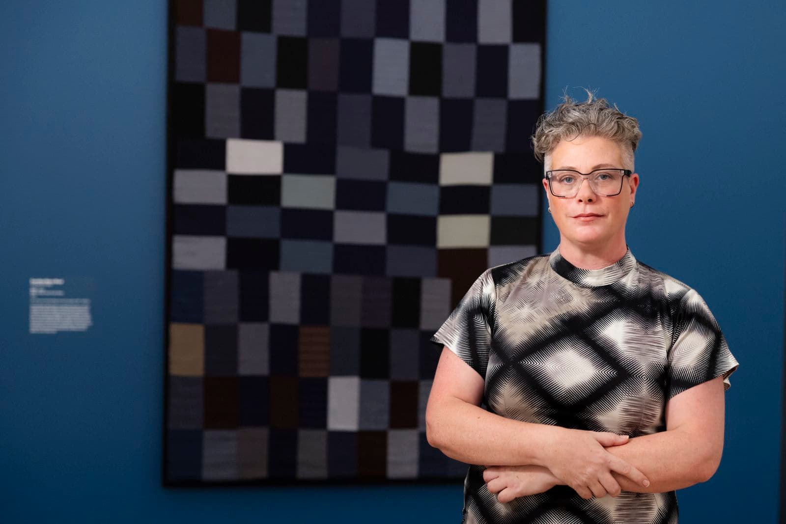 Curator stands in front of a quilt.
