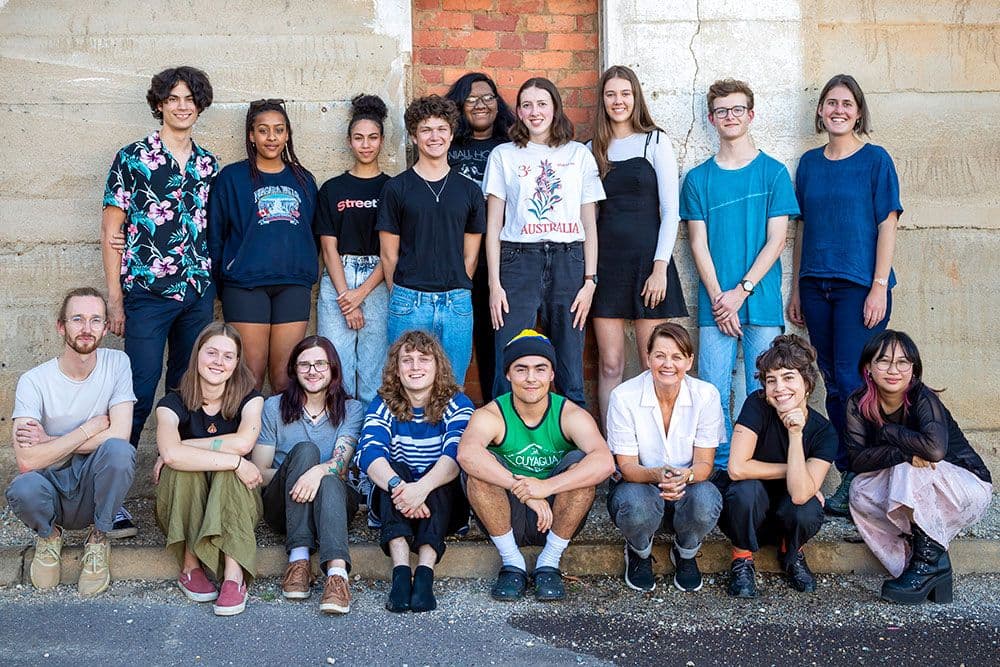 A group of young people stand posed in front of a wall