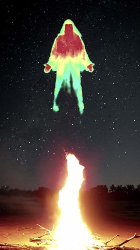 A digital image showing a hooded man levitating above a campfire