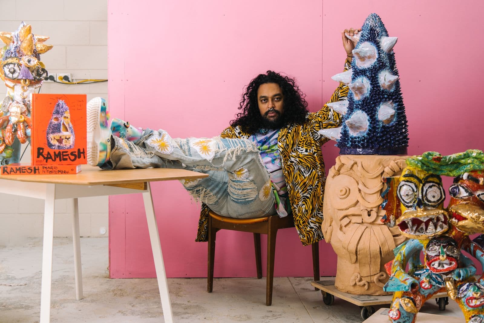 Artist Ramesh Mario Nithiyendran sits in his studio with various ceramic works.