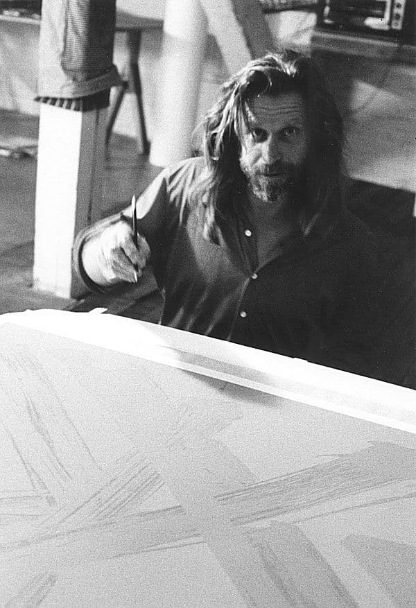 Black and white image of Mark di Suvero signing his work