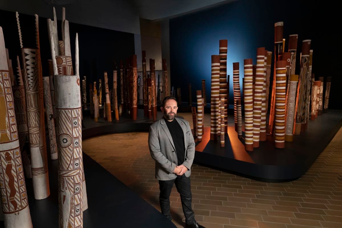 A man standing within an installation of 200 hollow log coffins from Central Arnhem Land