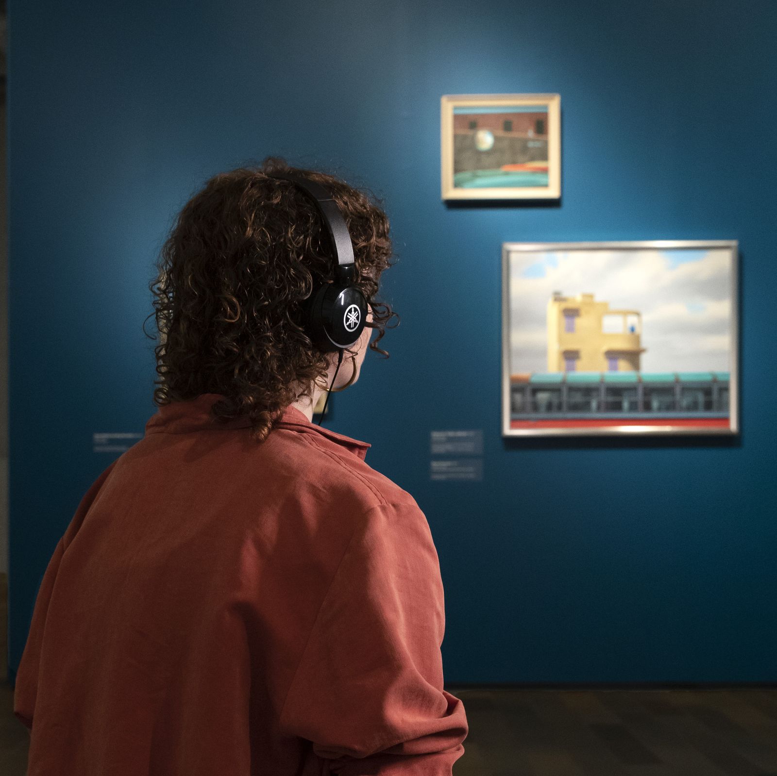 A photo of a woman sitting down listening to an audio tour.