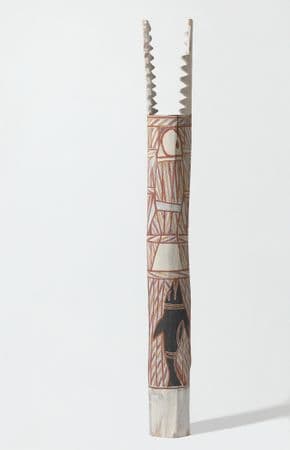 White pole with ochre, black and yellow patterning and teeth like protrusions from the pole's top