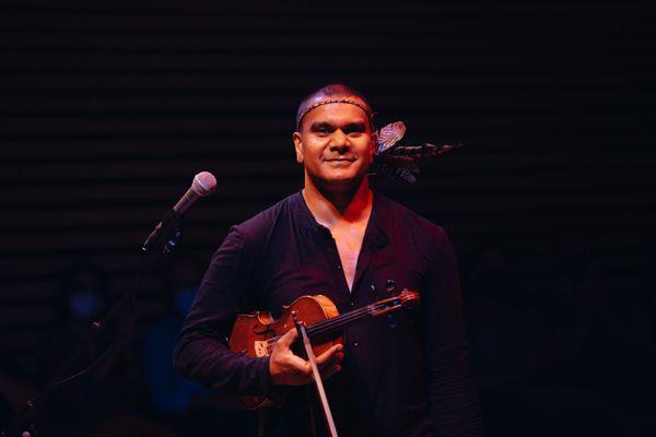 Photograph of a man standing under spotlights holding a violin
