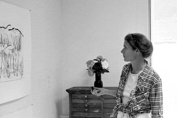 A woman in a room looking at artwork on a wall