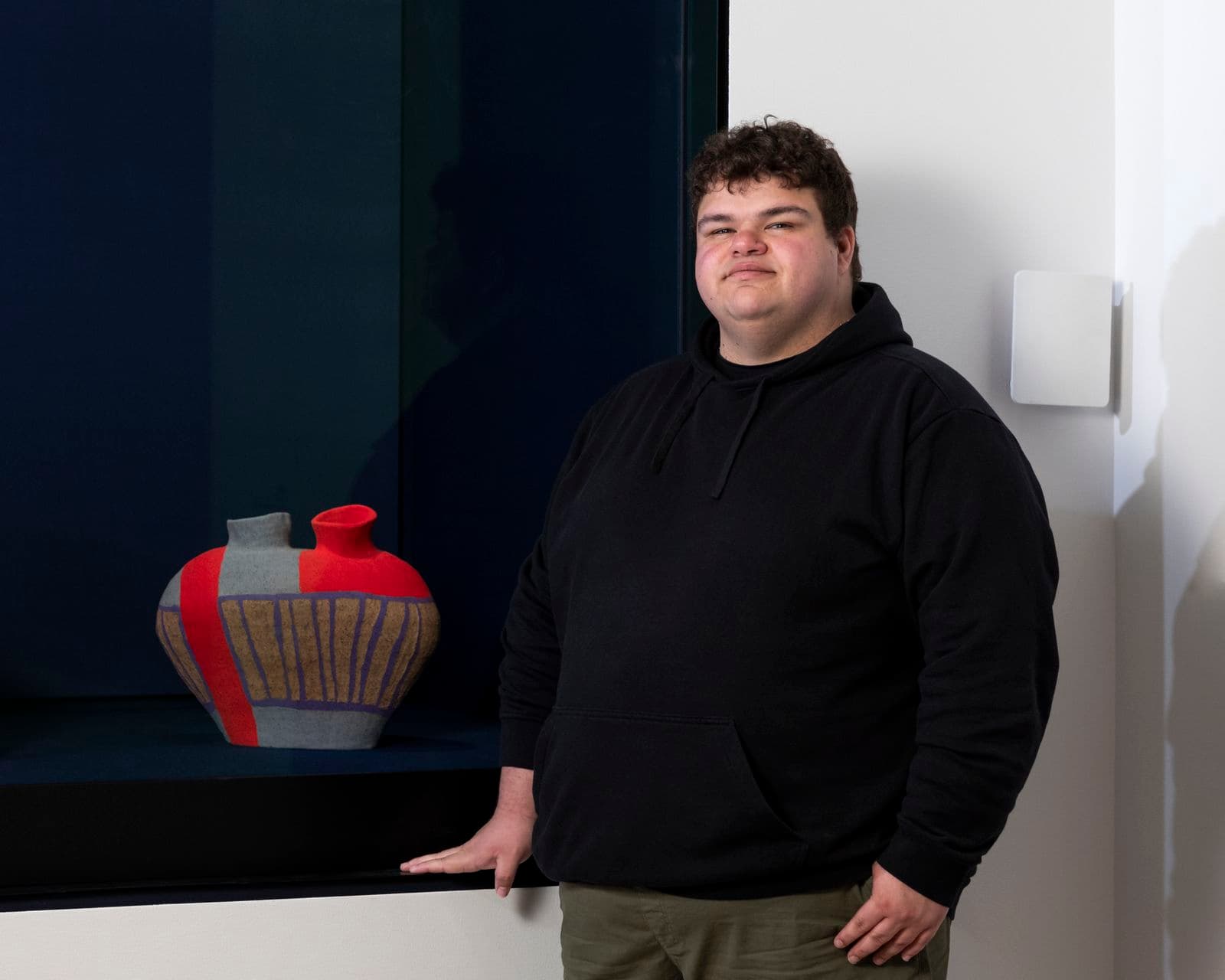 An artist portrait in front of a ceramics piece.