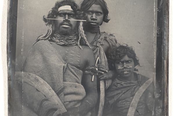 Photograph of an Indigenous Australian man in traditional dress and two younger children also in traditional clothing
