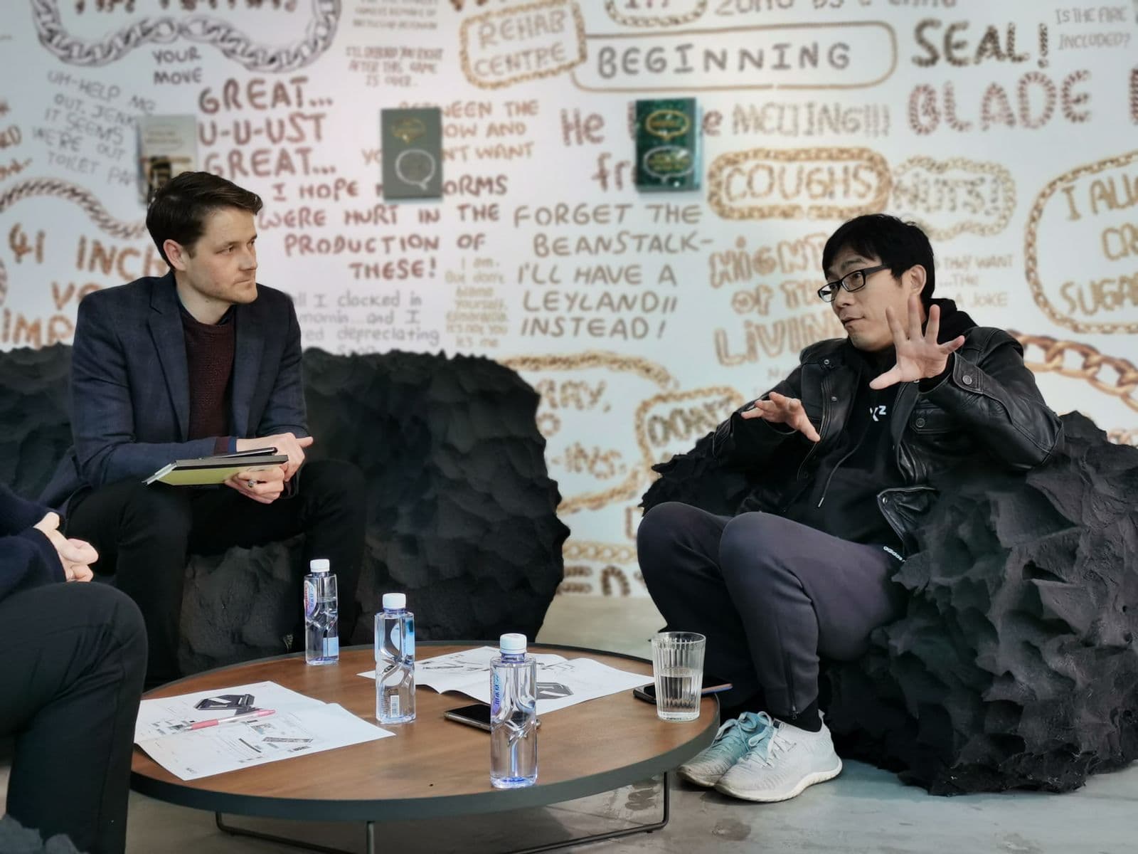 Two men sit on chairs talking