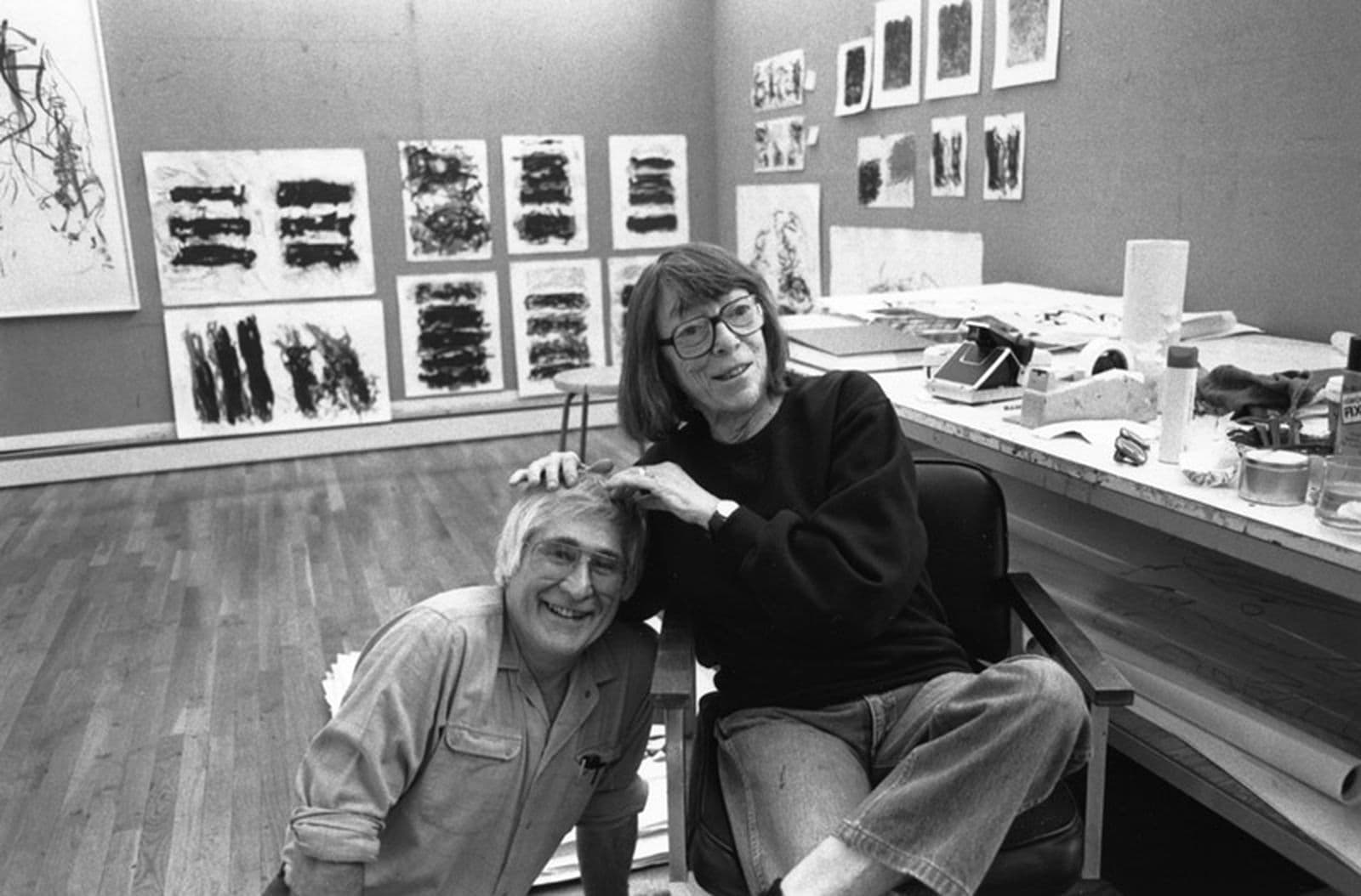 Kenneth Tyler and Joan Mitchell with proofs of Mitchell’s ‘Fields’, ‘Trees’ and ‘Weeds’ works hanging in the background.