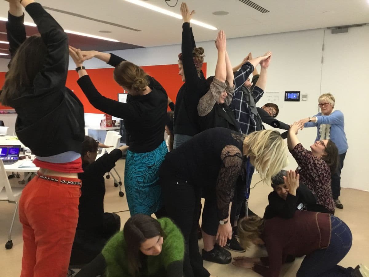 Group of people standing and crouching on the ground making shapes with their bodies