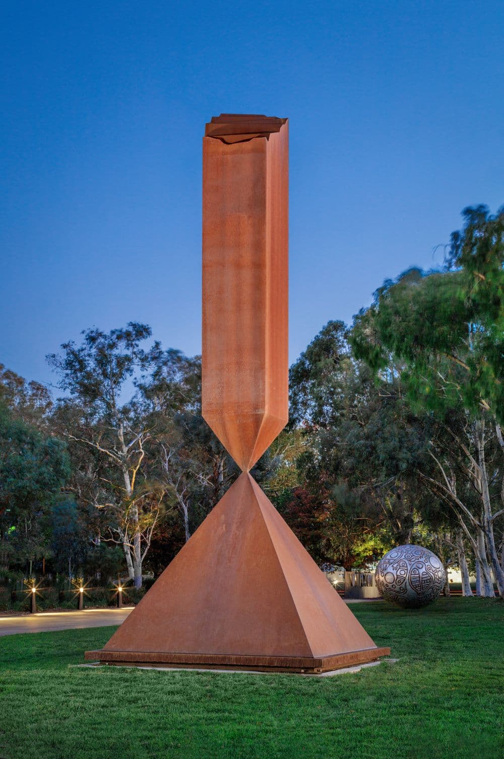 A large rusted brown obelisk balancing on a pyramid
