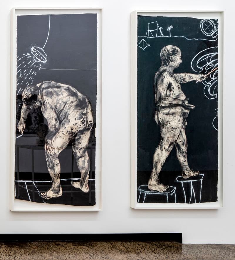 Black and white depiction of two nude male figures drawing on walls